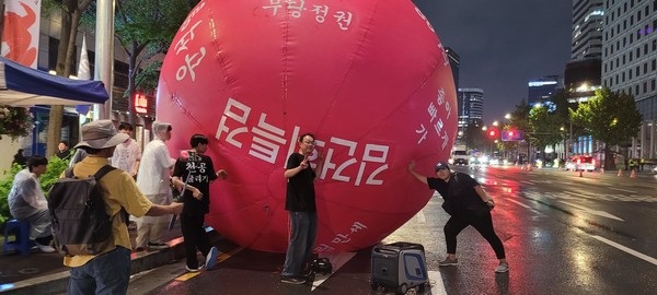 지난 16일 주말 서울 태평로에서 진행된 촛불집중행동에 등장한 지름 5m의 대형 빨간 고무공. 오종선 작가(가운데)의 10번째 개인전 '천공굴리기'가 시작됐다. [사진출처-오종선 작가 페이스북]