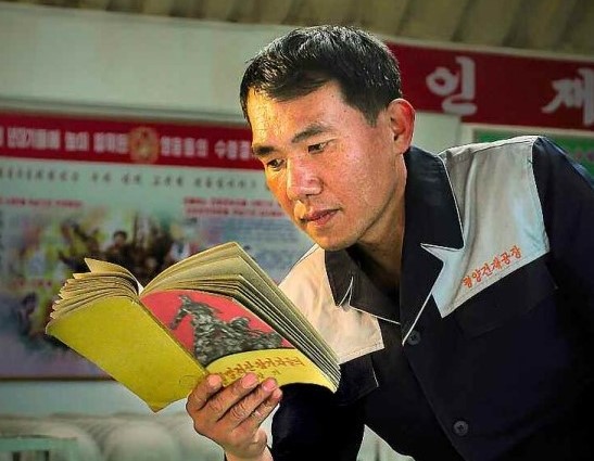 ‘항일빨찌산 참가자들의 회상기’를 읽고 있는 북한의 노동자. [사진-조선신보 갈무리]