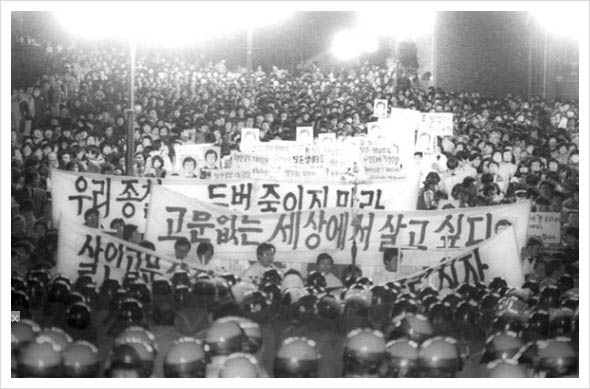 1987년 1월 14일에 치안본부 대공분실에 끌려가 조사를 받던 서울대 박종철 학생이 경찰에게 물고문을 받다 숨지면서 이를 규탄하는 투쟁이 거세게 타올랐고, ‘호헌철폐 독재타도’를 내건 6월항쟁의 도화선이 됐다. 6월 9일에는 시위를 벌이던 연세대 이한열 학생이 경찰이 쏜 최루탄에 맞아 의식불명이 되자 6월10일부터 전국적인 시위가 벌어지면서 민주항쟁으로 나아갔다. 사진은 명동성당 앞에서 거행된 ‘살인고문 전두환 정권 규탄대회’ 광경. [사진 제공 – 안영민]