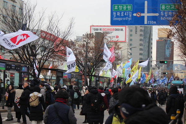 남영역 삼거리에서 용산 방향으로 가려는 행진 대열을 막는 경찰들과 대치하던 참가자들이 경찰이 세워둔 방어벽을 넘어 건너편 차선으로 넘어가고 있다. [사진-통일뉴스 이승현 기자]