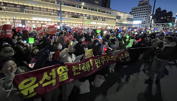 14일 오후 일본 도쿄 신주쿠역에서 열린 윤석열 대통령 탄핵 집회에서 한국 국회에서 탄핵안 가결 소식이 전해지자 참가자들이 환호하고 있다. [사진-통일뉴스 조정훈 통신원]