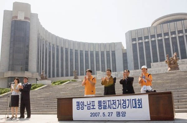 2007년 5월 민족21 주최로 평양에서 열린 평양-남포 통일자전거대회 개막식 광경. 단상의 맨왼쪽이 필자이고, 그 옆에 북측 민화협의 박경철 부회장이다. [사진 제공 – 안영민]