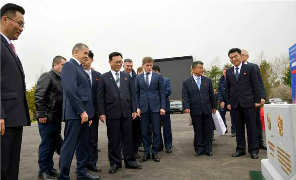 착공식 행사에 참가한 양측 인사들이 착공식 기념표식비를 보고 있다. [사진-노동신문]