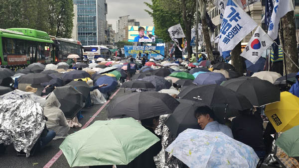 5시가 되어 본격적으로 빗방울이 떨어지자 손피켓을 든 참가자들은 일사불란하게 우산과 비옷으로 집회장을 덮었다. [사진 - 통일뉴스 하태한 통신원]