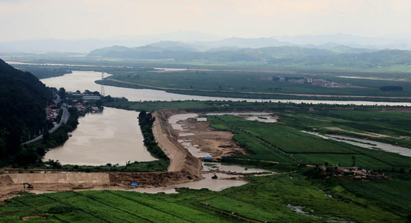 군인건설자들이 의주군 어적도에서 제방공사를 하고 있다. 어적도 위에 있는 섬이 구리도로 지난해 홍수피해를 복구하면서 새로운 주택이 들어서 있다. [사진 제공 - 포럼 평화공감]