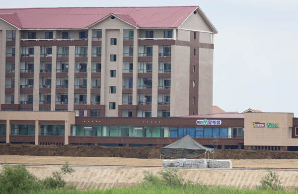 신의주시 위화도에 새로 건설된 살림집에 입주한 주민들이 유리창을 청소하는 모습이 보인다. 2층에는 양복점, 신문도서열람실 등 편의봉사시설이 들어서 있다. [사진 제공 - 포럼 평화공감]