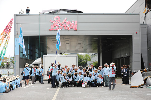 민주노총 26기 중앙통일선봉대 대원들이 한국옵티칼하이테크 건물을 배경으로 투쟁결의 사진을 남기고 있다. [사진제공-민주노총 중앙통일선봉대]