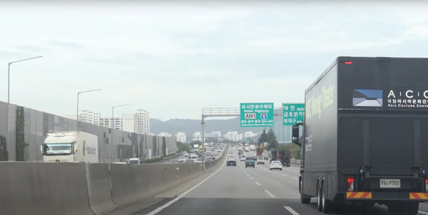 아시안하이웨이 표지판이 보이는 고속도로를 달리는 무대차량(Moving Theater) [사진-코리아-유라시아 로드런 공연 영상 갈무리]