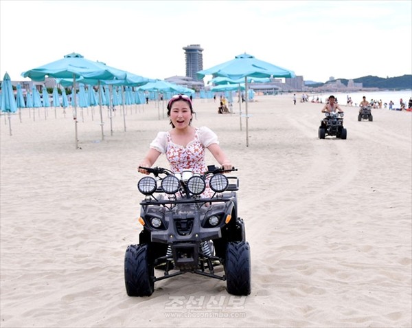 모래사장에서 오토바이를 타다. [사진-조선신보 갈무리]