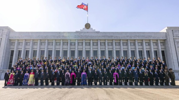 김정은 위원장이 국기가 날리는 의사당을 배경으로 경축행사 참가자들과 기념촬영을 했다. [사진-노동신문]
