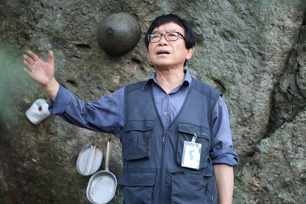  남녘현대사연구소 박동기 소장의 강연 뒤 배경으로, 바위에는 당시 총탄의 흔적과 철모, 군용 식기 등이 전시되어 있다. [사진제공-615산악회]