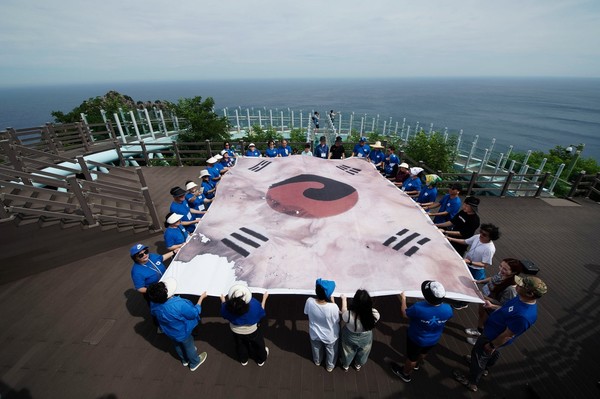 지난 달 30일 ′더민주 하나되는 대한민국′ 성원들이 독도에 입도해 대형 진관사 태극기 모형을 들고 ′독도를 보아야 대한민국을 본 것입니다′라는 주제로 독도 알리기 행사 진행 중인 장면.[사진-통일뉴스 위정량 통신원]