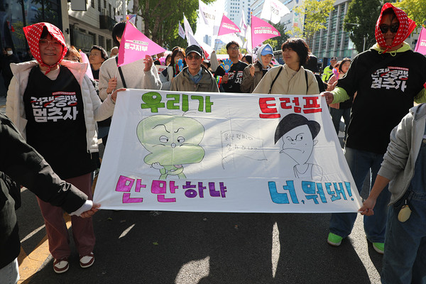 대회 참가자들이 만화 캐릭터 그림과 함께 큰 글씨로“우리가 만만하냐 트럼프, 너 뭐 돼!” 라는 문구를 담은 펼침막을 들고 행진하고 있다. [사진-통일뉴스 김래곤 통신원]