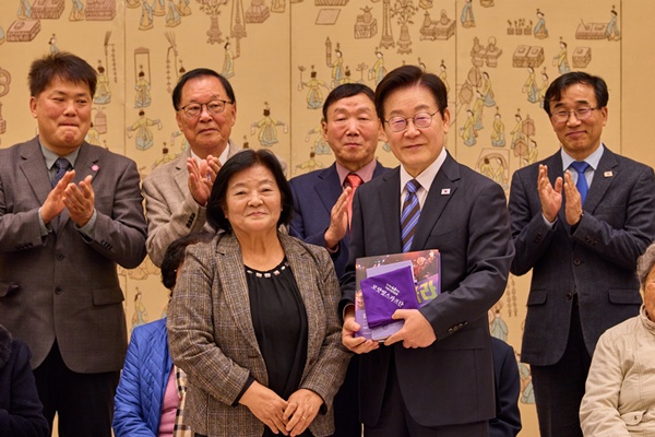 '민가협 40주년 기념 사진첩'을 선물 받은 이 대통령. 왼쪽은 조순덕 상임의장. [사진-대통령실]