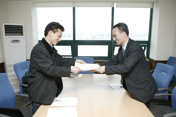 정창현 [민족21] 편집주간(오른쪽)은 2006년 4월 13일 개성공업지구관리위원회 사무실에서 북측 [통일신보] 관계자와 만나 기사교류합의서에 서명, 교환했다. [자료사진 - 통일뉴스]