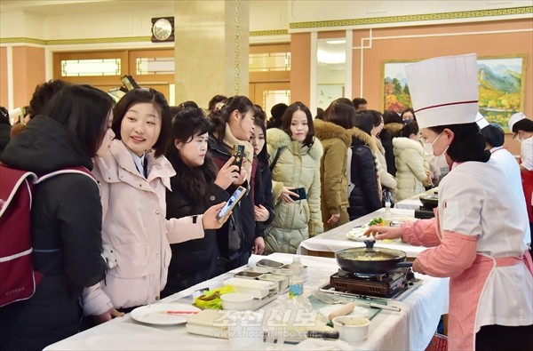 전국요리기술경연에서 평양시 가정주부들의 경연을 보는 참관자들의 모습. [사진-조선신보 갈무리]